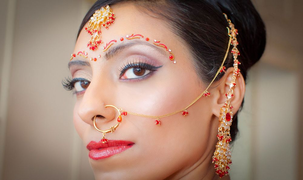 A beautiful Indian bride dressed in traditional Maang tikka, matha patti, bor, and borla facial jewellery